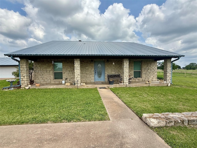 view of front of property featuring metal roof, a front lawn, and stone siding
