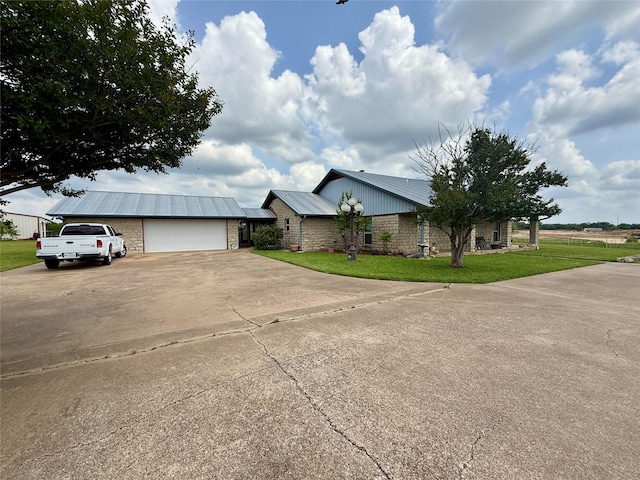 ranch-style house with metal roof, a front yard, driveway, and stone siding