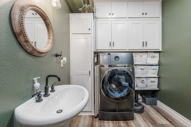 11900 Wind Hollow Ct, Tolar, TX 76476 - laundry room with wood finished floors, washer / dryer, a textured wall, baseboards, and cabinet space