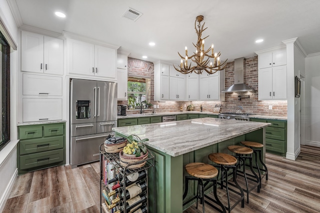 11900 Wind Hollow Ct, Tolar, TX 76476 - kitchen featuring stainless steel appliances, wall chimney range hood, green cabinets, a chandelier, and white cabinetry