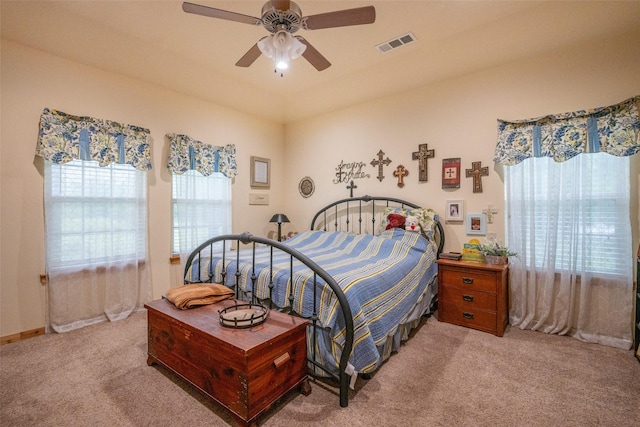 carpeted bedroom with a ceiling fan and visible vents
