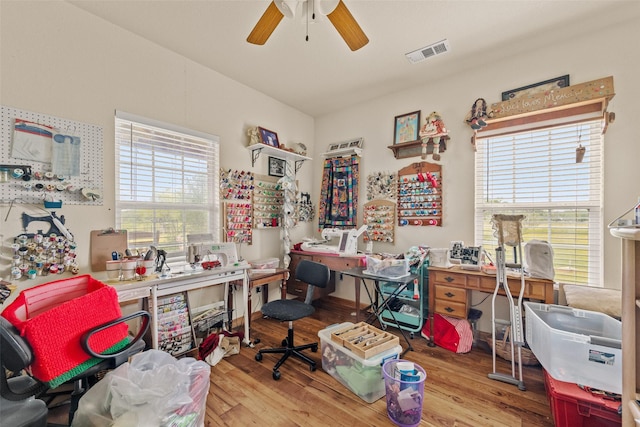 office area featuring a ceiling fan, visible vents, a wealth of natural light, and wood finished floors