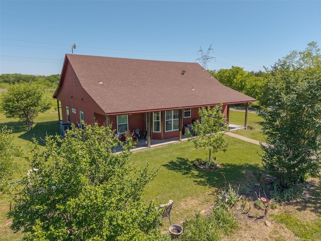rear view of house featuring a lawn, a shingled roof, and a patio area