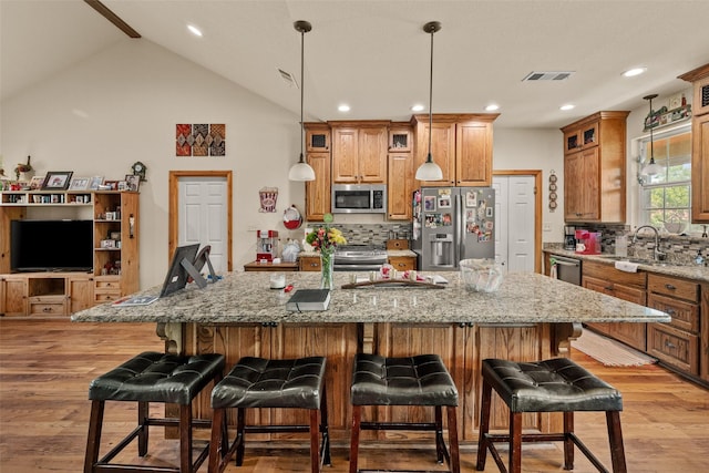 kitchen featuring a sink, light wood-style floors, brown cabinetry, visible vents, and appliances with stainless steel finishes