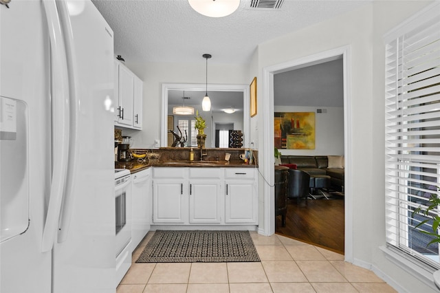 kitchen featuring white appliances, white cabinetry, dark countertops, and hanging light fixtures