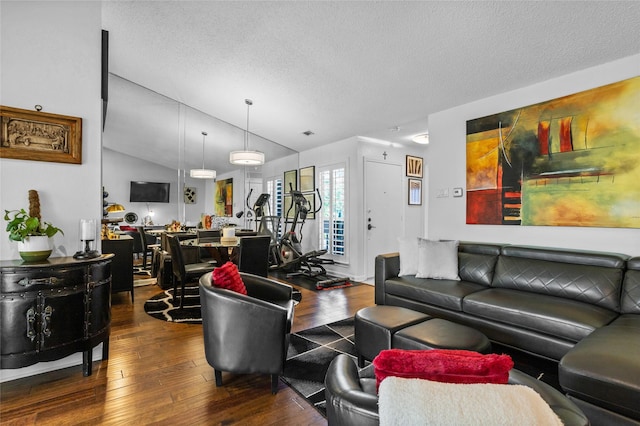 living area with visible vents, a textured ceiling, vaulted ceiling, and hardwood / wood-style floors