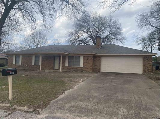 ranch-style house with driveway, a chimney, brick siding, and a garage