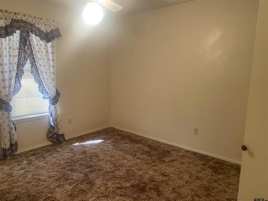 carpeted empty room with ceiling fan and baseboards