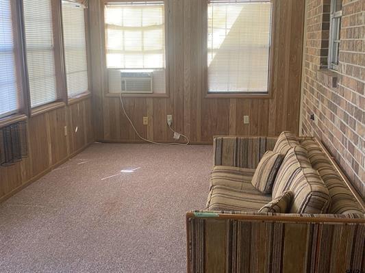 carpeted living room featuring wood walls and cooling unit