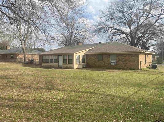 rear view of property with fence, a lawn, and central air condition unit