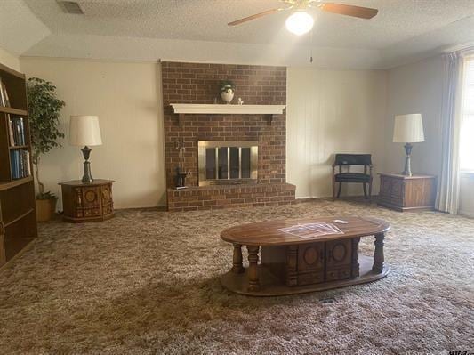 carpeted living area with a fireplace, a textured ceiling, ceiling fan, and visible vents
