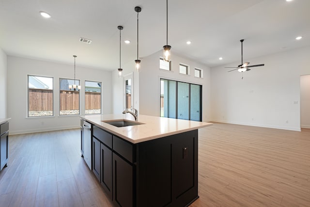 kitchen featuring light wood finished floors, a sink, visible vents, stainless steel dishwasher, and ceiling fan with notable chandelier