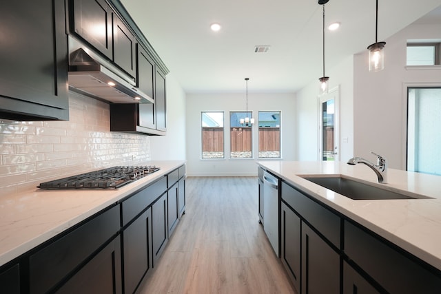 kitchen featuring a sink, appliances with stainless steel finishes, visible vents, under cabinet range hood, and light wood-type flooring
