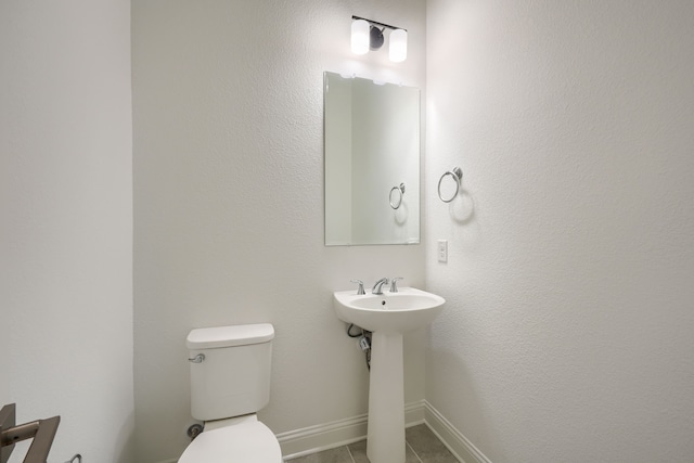 half bathroom featuring baseboards, toilet, and tile patterned flooring