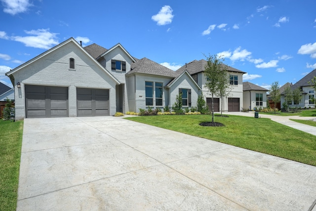 view of front of property featuring a front lawn, driveway, a shingled roof, and brick siding