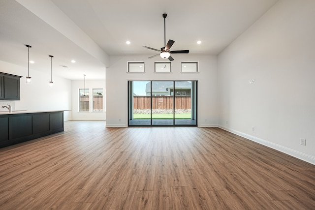 unfurnished living room with baseboards, wood finished floors, and a ceiling fan
