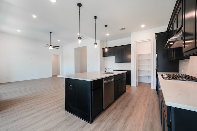 kitchen with under cabinet range hood, appliances with stainless steel finishes, dark cabinetry, a sink, and visible vents
