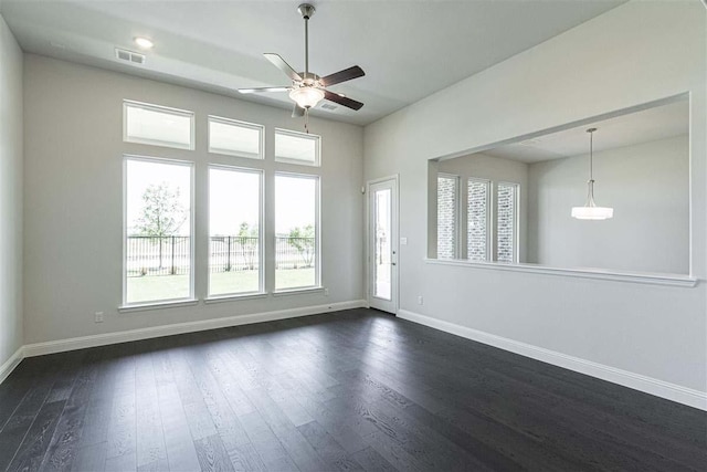 unfurnished room with dark wood-style floors, visible vents, ceiling fan, and baseboards