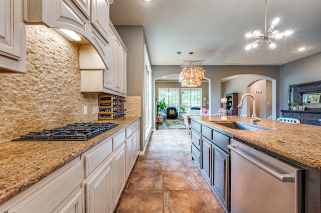 881 Willowmist Dr, Prosper, TX 75078 - kitchen with dishwasher, black gas cooktop, arched walkways, a chandelier, and backsplash