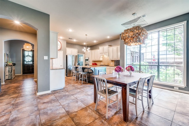 881 Willowmist Dr, Prosper, TX 75078 - dining room with a chandelier, arched walkways, recessed lighting, and light tile patterned floors