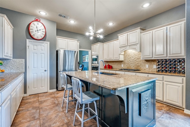 881 Willowmist Dr, Prosper, TX 75078 - kitchen featuring appliances with stainless steel finishes, backsplash, a chandelier, light stone countertops, and a breakfast bar area