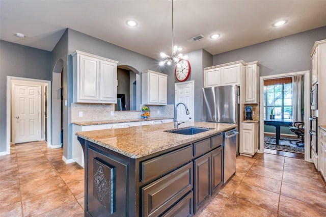 881 Willowmist Dr, Prosper, TX 75078 - kitchen with arched walkways, white cabinetry, a kitchen island with sink, backsplash, and recessed lighting