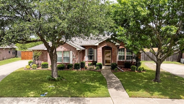 view of front facade with concrete driveway, a shingled roof, fence, brick siding, and a front lawn