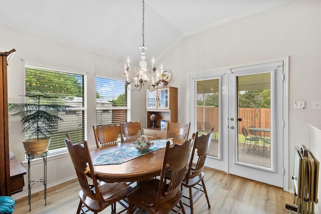 dining room featuring lofted ceiling, light wood-type flooring, ornamental molding, and a notable chandelier