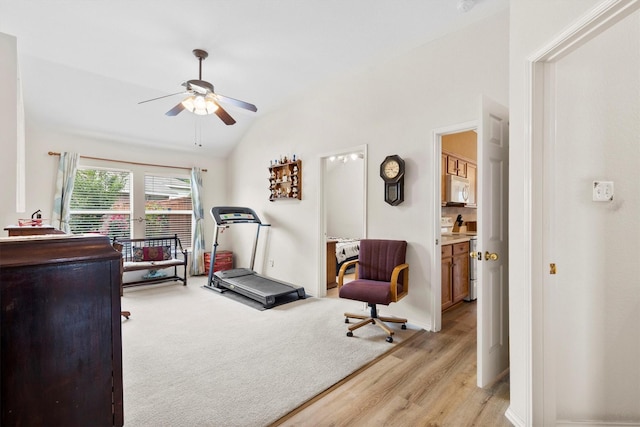 workout area featuring light wood finished floors, a ceiling fan, and lofted ceiling