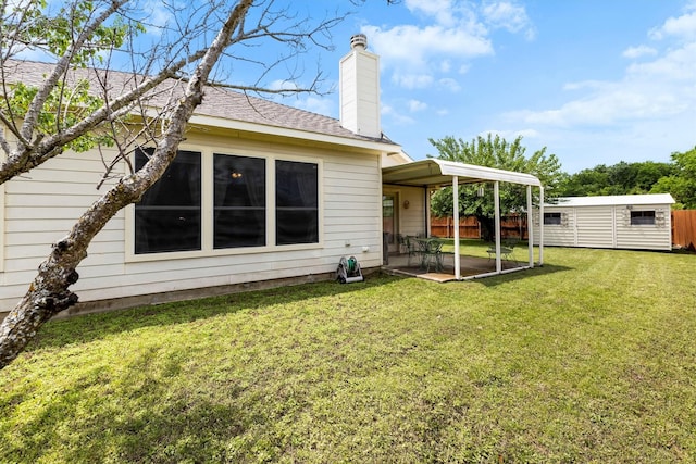 rear view of property with fence, a chimney, a lawn, and a patio