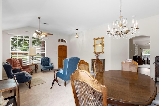 dining room with visible vents, vaulted ceiling, arched walkways, light colored carpet, and ceiling fan with notable chandelier