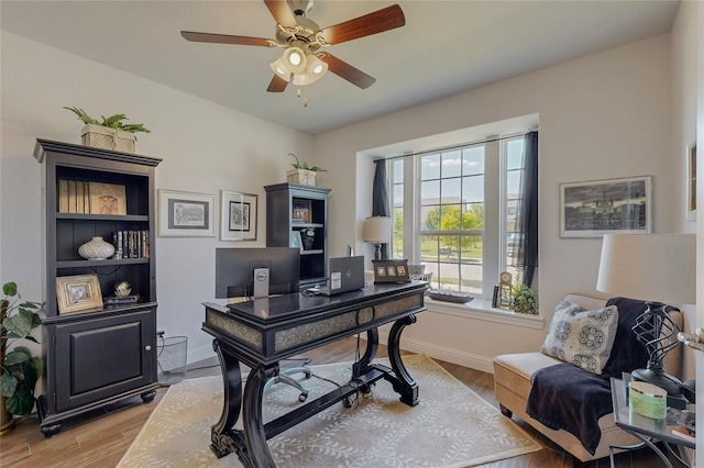 office area with ceiling fan, baseboards, and light wood-type flooring
