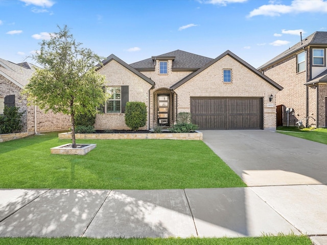 french provincial home with driveway, an attached garage, a front yard, and brick siding
