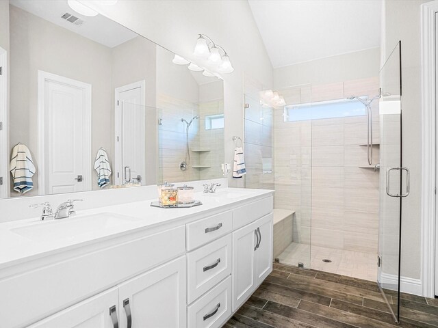 bathroom featuring a shower stall, a sink, wood tiled floor, visible vents, and vaulted ceiling