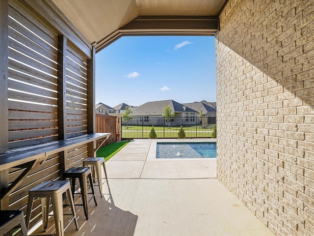 view of swimming pool with outdoor dry bar, fence, a residential view, and a patio area