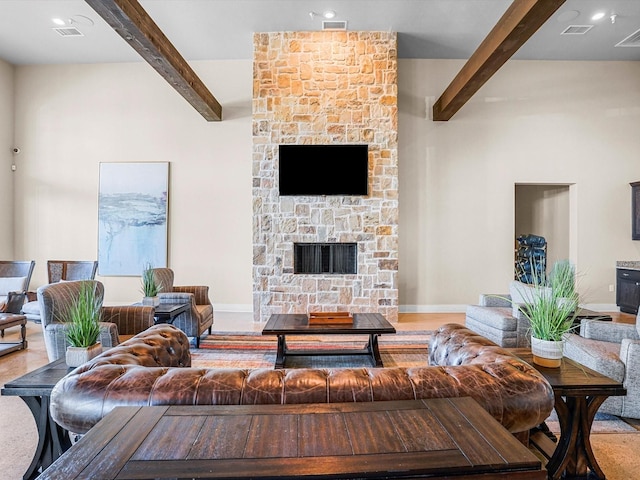 living room featuring beamed ceiling, visible vents, and a fireplace
