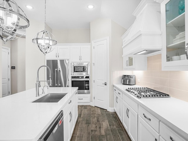 kitchen with a sink, an inviting chandelier, stainless steel appliances, custom range hood, and light countertops