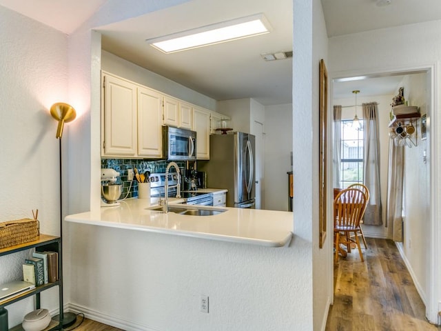 kitchen featuring appliances with stainless steel finishes, wood finished floors, decorative backsplash, and light countertops