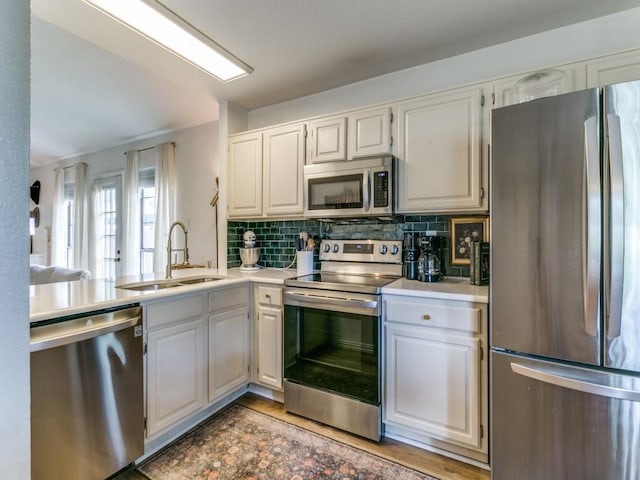 kitchen featuring tasteful backsplash, stainless steel appliances, light countertops, and a sink