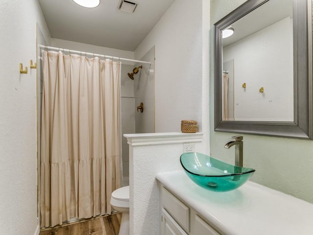 full bathroom featuring toilet, vanity, visible vents, and wood finished floors