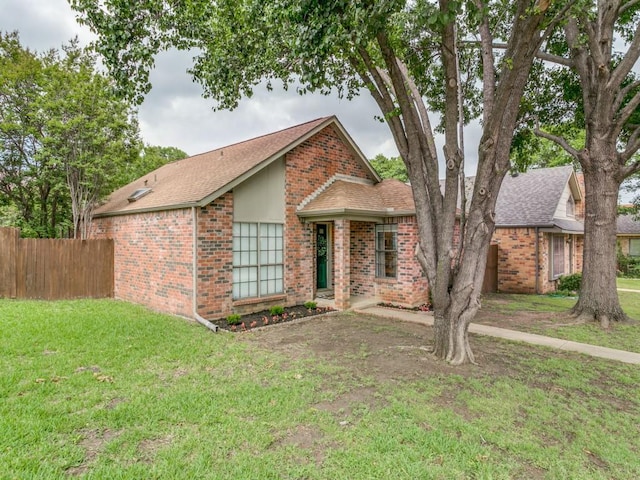 view of front of home featuring brick siding, fence, a front yard, and roof with shingles