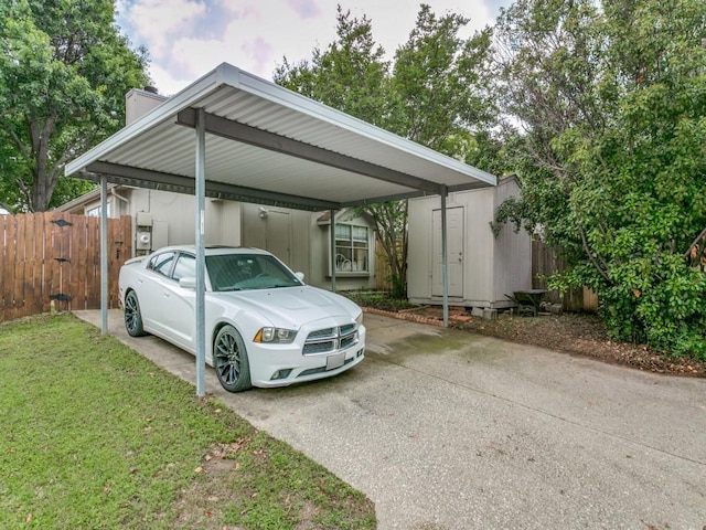 view of vehicle parking featuring fence, a storage shed, driveway, and a detached carport