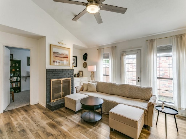living area with a ceiling fan, vaulted ceiling, wood finished floors, and a fireplace
