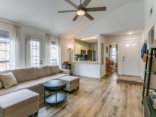 living room with light wood-type flooring, ceiling fan, lofted ceiling, and a healthy amount of sunlight