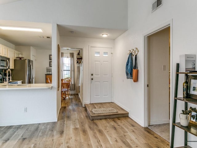 foyer with visible vents, light wood-style flooring, and baseboards