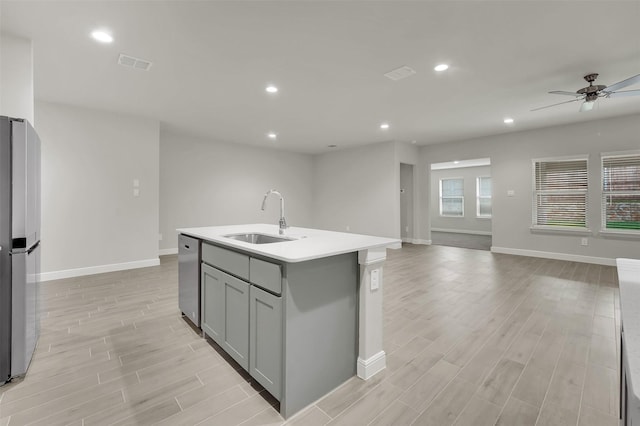 kitchen featuring open floor plan, a sink, stainless steel appliances, and gray cabinets