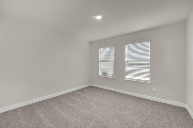 empty room featuring carpet and baseboards