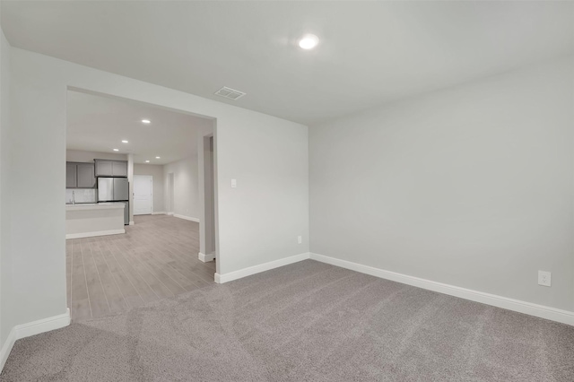 unfurnished room with visible vents, recessed lighting, light carpet, and baseboards