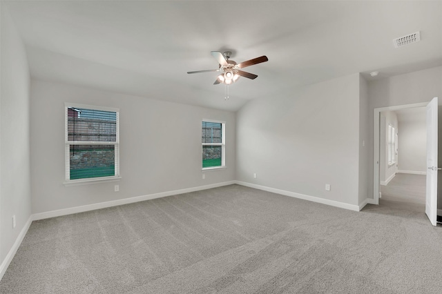 carpeted spare room with a ceiling fan, visible vents, a wealth of natural light, and baseboards