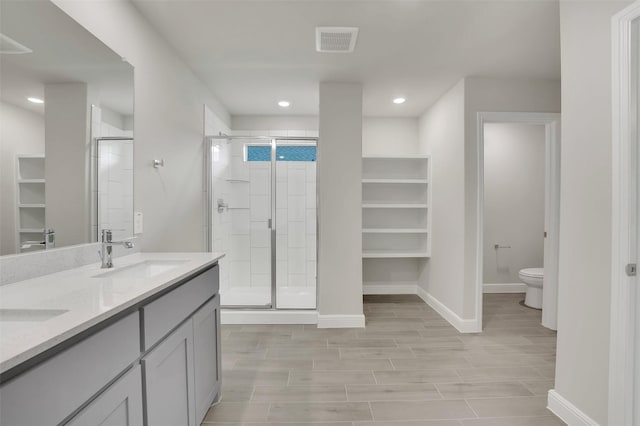 bathroom featuring toilet, a sink, a shower stall, and baseboards